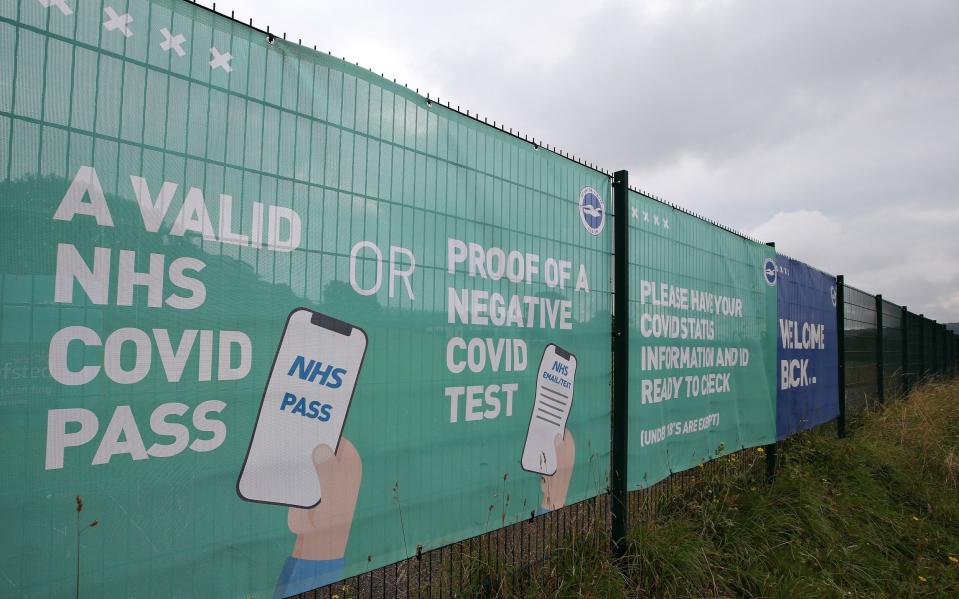 NHS Covid Pass and Negative Covid test advice is seen on a banner outside the stadium prior to the Premier League match between Brighton & Hove Albion and Watford at American Express Community Stadium on August 21, 2021 in Brighton, England - GETTY IMAGES