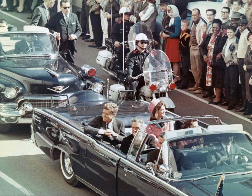 Bettmann Archive The Kennedys ride a limousine through Dallas on Nov. 22, 1963. Secret Service Agent Clint Hill walks beside the vehicle behind them, in a black suit and sunglasses
