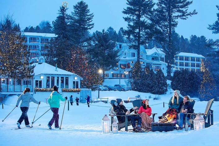 Cross Country skiers and people around a fire-pit at Mirror Lake Inn Resort and Spa