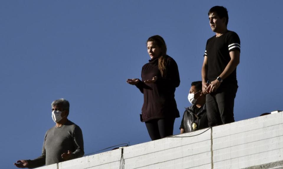 Bolivia’s interim president, Jeanine Áñez, centre, prays on a rooftop as Monsignor Fernando Bascope leads a Good Friday procession on a truck through the streets of La Paz on 10 April.