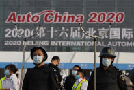 Security guards wearing masks and armed with restrainers stand guard at the entrance to the Auto China 2020 show in Beijing, China on Saturday, Sept. 26, 2020. The auto show, the first major in-person sales event for any industry since the coronavirus pandemic began, opens Saturday in a sign the ruling Communist Party is confident China has contained the disease. Still, automakers face intensive anti-virus controls including quarantines for visitors from abroad and curbs on crowd sizes at an event that usually is packed shoulder-to-shoulder with spectators. (AP Photo/Ng Han Guan)