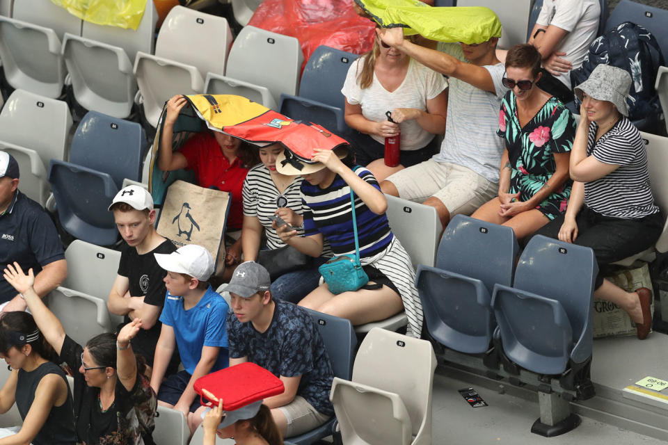 Spectators at the Australian Open seek shade during a break in play on Thursday. Source: AAP