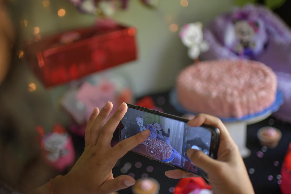 Ada Mendoza, de 24 años, toma una foto de las decoraciones en su baby shower mientras su familia nuclear, su pareja y amigos cercanos celebran en la casa de sus padres en el barrio Catia de Caracas, Venezuela, el sábado 5 de septiembre de 2020. (AP Foto/Matias Delacroix)