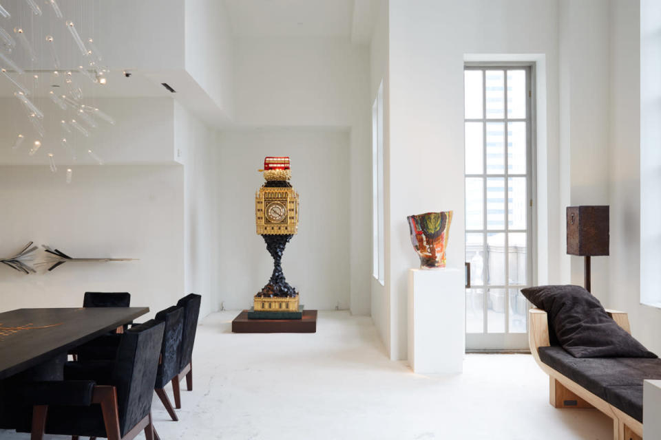 Large table: Table Tribal by Ingrid Donat (2015). Chairs: Committee Armchair by Pierre Jeanneret (1960). Wall sculpture: Doors I by Vincent Dubourg (2010). Chandelier: Flylight by Studio Drift (2015). Clock: Big Ben (Aftermath) by Studio Job (2009-2014). Vase: Untitled 01 (Red, Black, Blue, Yellow) by Roger Herman (n.d.). Floor lamp: Jewel by Atelier van Lieshout (2011). Bench: Double Bubble by Rick Owens (2013).