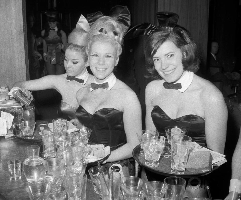 FILE - In this Jan. 15, 1963 file photo, Playboy Bunnies Elka Hellmann, from left, Monica Schaller and Sabrina Scharf serve drinks at New York's Playboy Club. The tightly corseted Playboy Bunnies, with rabbit tails and ears, will soon be back in business in New York City. Three decades after the original Playboy Club closed in Manhattan, a new club will debut later this year in a hotel a few blocks from Times Square. (AP Photo/John Lent, File)