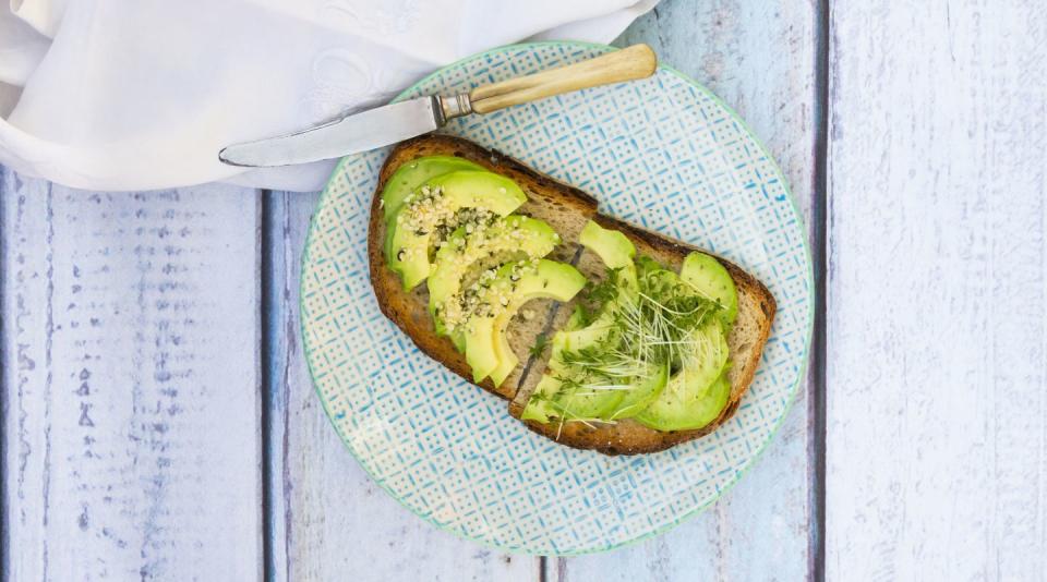 avocado toast with sprouts and chia seeds on a blue plate on a blue wooden table