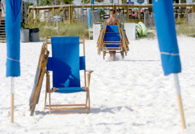 An employee of a local beach vendor moves chairs in Walton County. County commissioners next month are expected to consider changes to their beach activities ordinance.