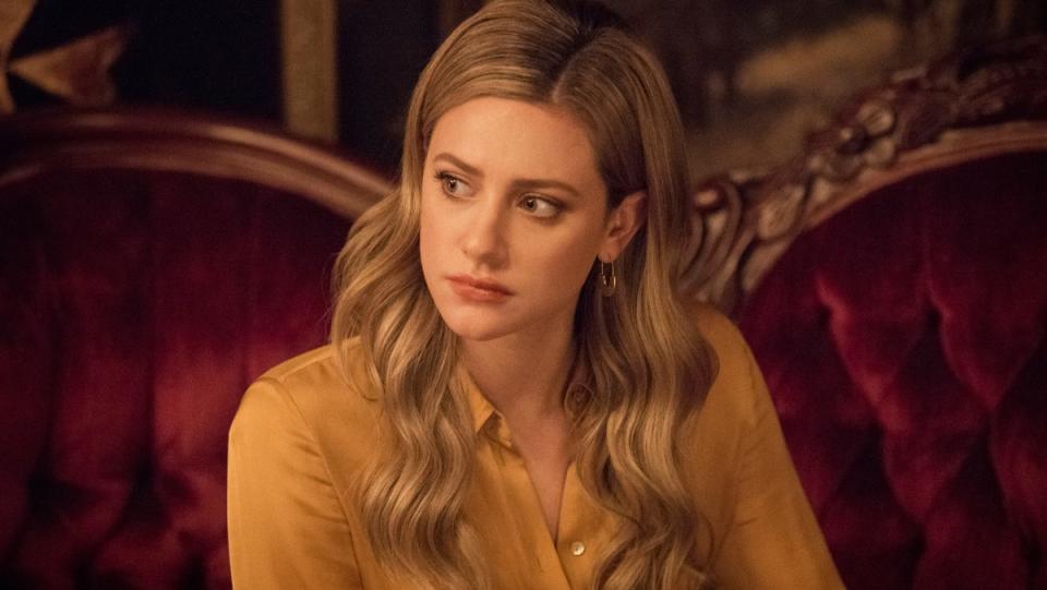 Betty Cooper wears a yellow sweater and has long hair in a scene from Riverdale.