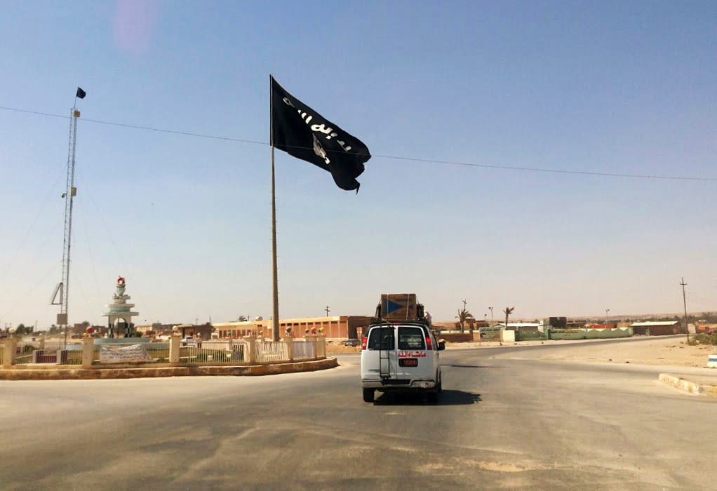 A motorist passes by a flag of the Islamic State group in central Rawah, 175 miles northwest of Baghdad, Iraq, July 22, 2014. Members of the global coalition fighting the Islamic State group met in Morocco on Wednesday, May 11, 2022, to discuss ongoing efforts in the campaign. (AP Photo, File)