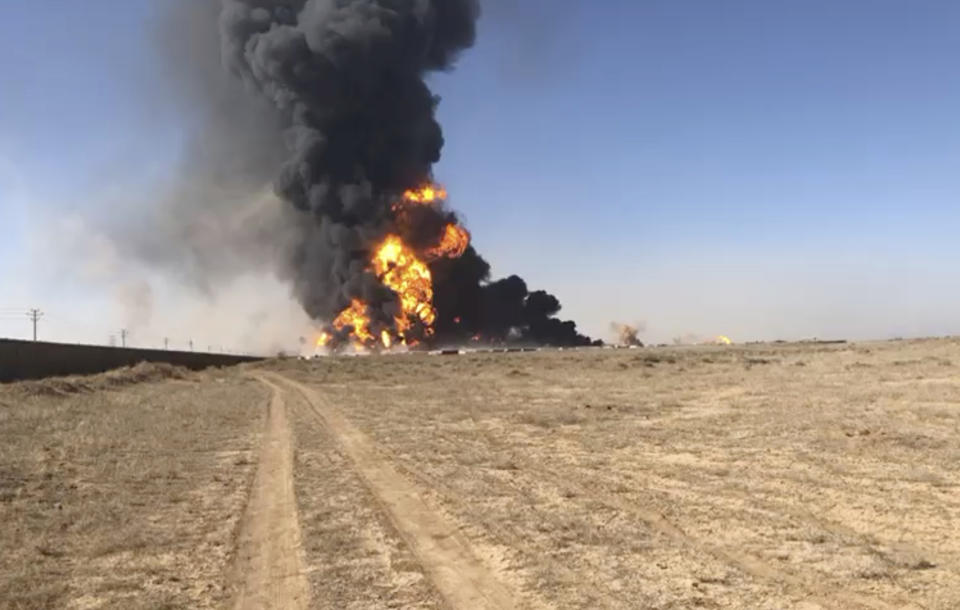 In this still image taken from video, smoke rises from fuel tankers at the Islam Qala border with Iran, in Herat Province, west of Kabul, Afghanistan, Saturday, Feb. 13, 2021. A fuel tanker exploded Saturday at the Islam Qala crossing in Afghanistan's western Herat province on the Iranian border, injuring at least seven people and causing a massive fire that consumed more than 500 trucks carrying natural gas and fuel, according to Afghan officials and Iranian state media. (AP Photo)