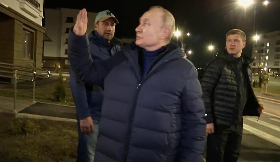 In this photo taken from video released by Russian TV Pool on Sunday, March 19, 2023, Russian President Vladimir Putin waves local residents after visiting their new flat during his visit to Mariupol in Russian-controlled Donetsk region, Ukraine. Putin has traveled to Crimea to mark the ninth anniversary of the Black Sea peninsula's annexation from Ukraine. (Pool Photo via AP)