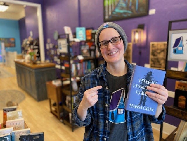 Kelly D. Holstine holds a book at WordHaven BookHouse.