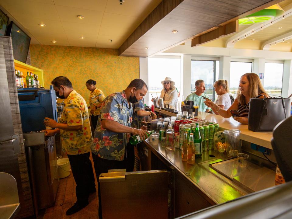 People ordering drinks at a bar while bartenders are working.