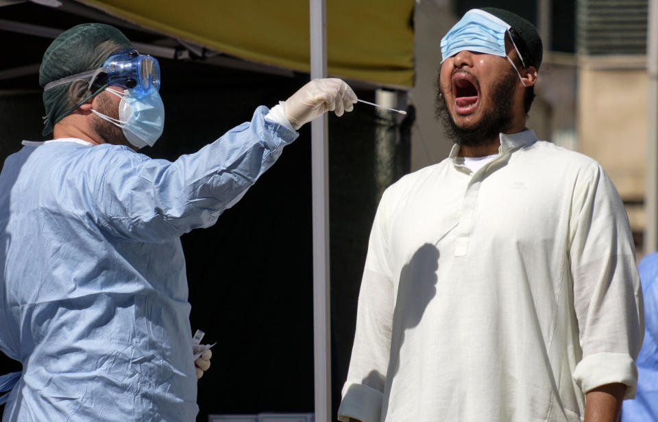 A member of the Bangladeshi immigrant community, right, has a swab being taken to test for COVID-19 outside a healthcare center in Rome, Thursday, July 9, 2020. Italy, the onetime European epicenter of the outbreak, went on alert about possible infections in the Bangladeshi immigrant community after a cluster of about a dozen cases was traced to a recently returning Bangladeshi worker in Rome. (Mauro Scrobogna/LaPresse via AP)