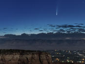 Comet Neowise soars in the horizon of the early morning sky in this view from the near the grand view lookout at the Colorado National Monument west of Grand Junction, Colo., Thursday, July 9, 2020. The newly discovered comet is streaking past Earth, providing a celestial nighttime show after buzzing the sun and expanding its tail. (Conrad Earnest via AP)