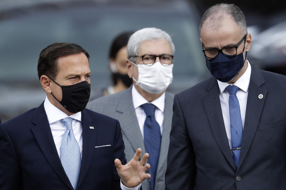 Sao Paulo Gov. Joao Doria, left, speaks to the Director of Brazil's National Health Surveillance Agency Antonio Barra, upon his arrival to the agency's headquarters for a meeting on the CoronaVac vaccine, in Brasilia, Brazil, Wednesday, Oct. 21, 2020. Brazil’s President Jair Bolsonaro rejected on Wednesday the announced purchase of 46 million doses of the potential vaccine being developed by a Chinese company and tested in Sao Paulo, a state governed by his political rival, prompting concern he was allowing politics to steer public health decisions. (AP Photo/Eraldo Peres)