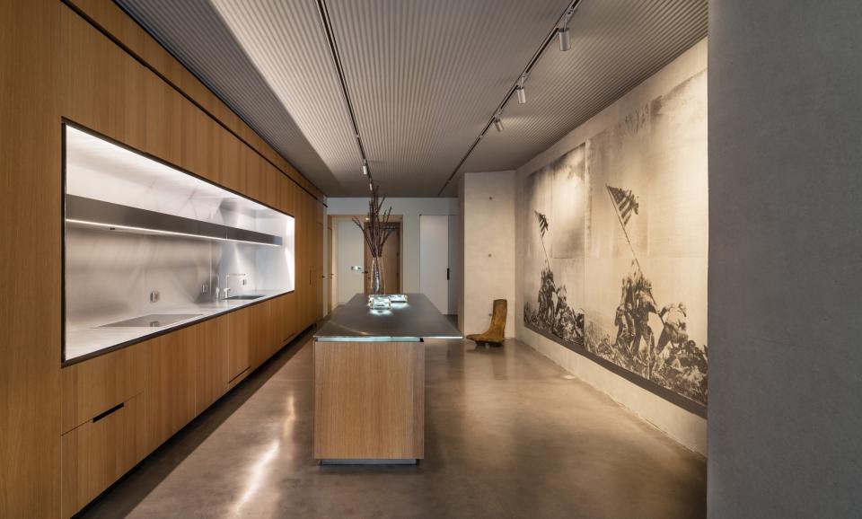 The large-scale kitchen of the three-bedroom model is ideal for entertaining, and custom ridges in the concrete throughout the lofts make for flexible lighting options. Here, a mural by the Bruce High Quality Foundation graces one wall.