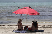 People sit on Hollywood Beach during the new coronavirus pandemic, Thursday, July 2, 2020, in Hollywood, Fla. In hard-hit South Florida, beaches from Palm Beach to Key West will be shut down for the Fourth of July holiday weekend. (AP Photo/Lynne Sladky)