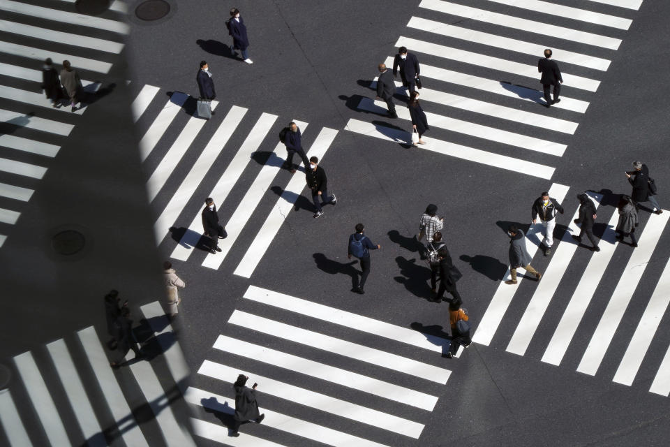 People wearing protective masks to help curb the spread of the coronavirus walk along a pedestrian crossing Wednesday, March 3, 2021, in Tokyo. The Japanese capital confirmed more than 310 new coronavirus cases on Wednesday. (AP Photo/Eugene Hoshiko)