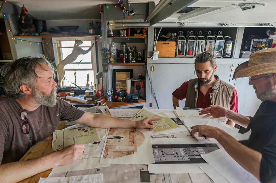 Co-creator John Dunivant, co-creator Daniel Land and Brett Carson look over renderings, blueprints and plans for the upcoming Space Dive 313, during the build at Carson’s home in Birmingham, April 14, 2024. Dunivant is an illustrator/artist with a background in architecture, painting, sculpture and world building, while Land is a special effects filmmaker.