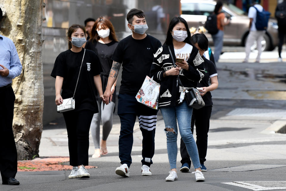 People are seen wearing face masks in Sydney on Monday amid a spike in cases across the city.