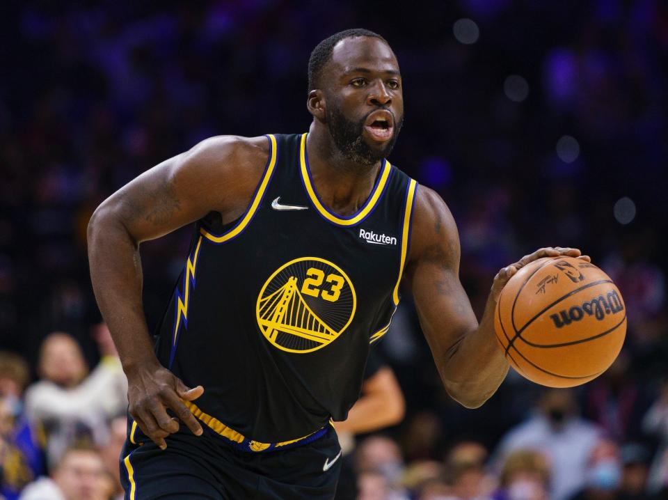 Draymond Green looks up the floor while dribbling the ball.