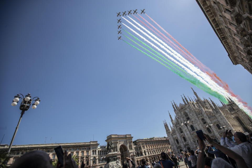 People gather to look at the Frecce Tricolori aerobatic squad of the Italian Air Force fly over Milan's Duomo cathedral, northern Italy, Monday, May 25, 2020 on the occasion of the 74th anniversary of the founding of the Italian Republic on June 2, 1946. This year the acrobatic squad will fly over several Italian cities to bring a message of unity and solidarity during the coronavirus pandemic.(AP Photo/Luca Bruno)