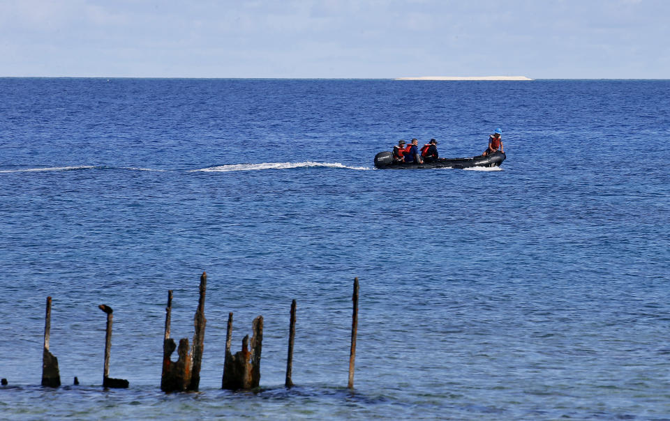 FILE - In this April 21, 2017, photo, engineers from NAMRIA, the central mapping agency of the Philippine Government, survey the area around the Philippine-claimed Thitu Island with a sandbar sitting on the horizon off the disputed South China Sea in western Philippines. Ships from the Chinese navy and coast guard along with fishing boats from its maritime militia have been deployed to keep watch on Philippine development work on the island of Thitu. (AP Photo/Bullit Marquez, File)