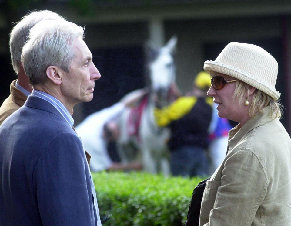 FILE - The Rolling Stones drummer Charlie Watts, second left, and wife Shirley, right, watch horses on the paddock at the Sluzewiec horse racing track in Warsaw, Poland, Saturday, May 25, 2002. Shirley Ann Watts, a former art student and prominent breeder of Arabian horses who met drummer Charlie Watts well before he joined the Rolling Stones and with him formed one of rock's most enduring marriages, has died at age 84. "Shirley died peacefully on Friday 16th December in Devon after a short illness surrounded by her family," her family announced Monday, Dec. 19, 2022. (AP Photo/Alik Keplicz, File)