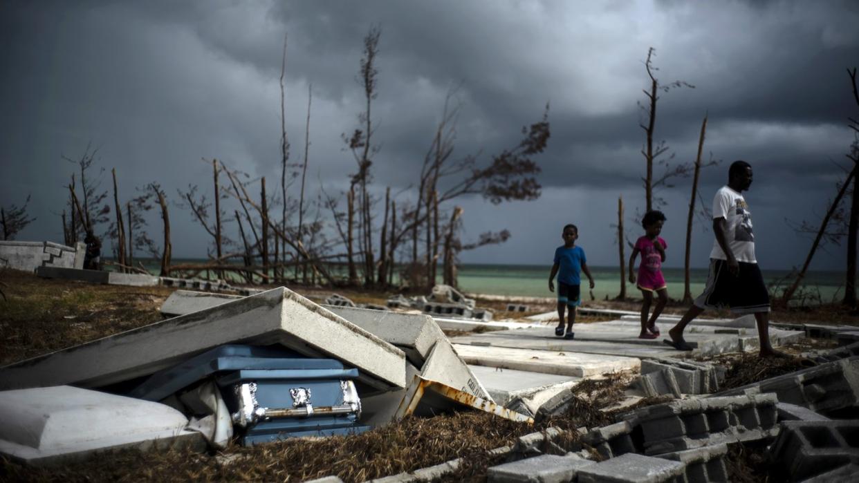 Menschen gehen an den Trümmern auf einem Friedhof auf den Bahamas vorüber. Foto: Ramon Espinosa/AP