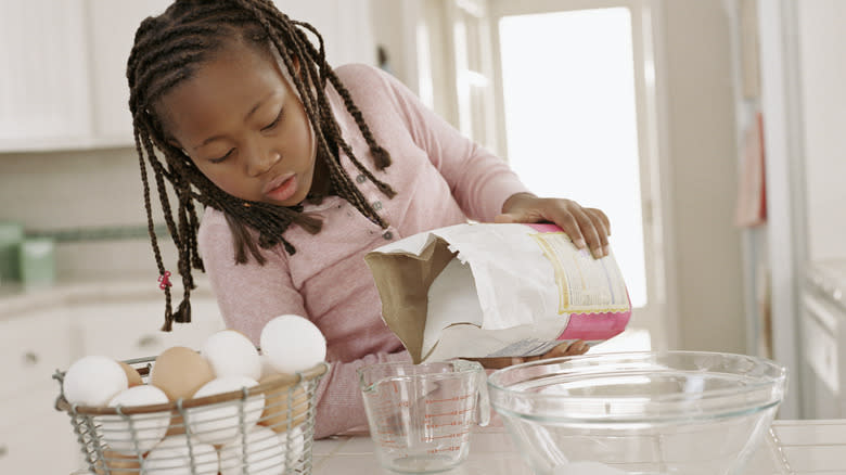 Person pouring sugar into bowl