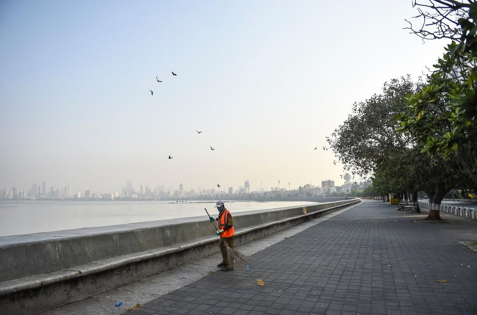 Mumbai: A municipal worker in Mumbai on Thursday, 15 April, cleans a deserted area near the sea front at Marine Drive during restrictions imposed by the state government amid rising COVID-19 coronavirus cases.