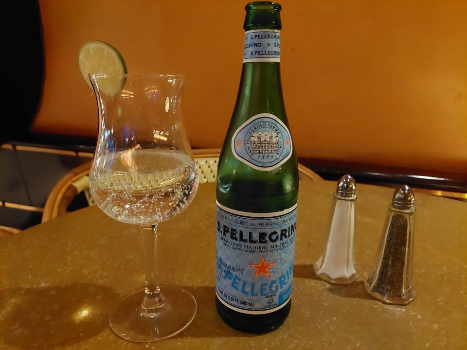A photo of a bottle of San Pellegrino and a glass of sparkling water