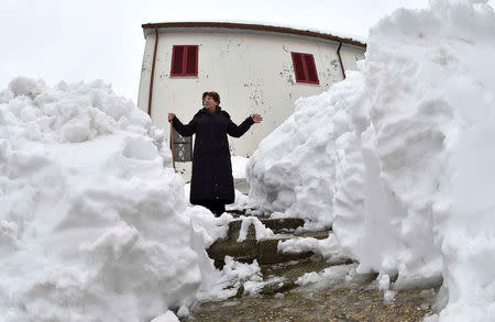 A woman removes snow in the town of Farindola, central Italy, following a series of earthquakes and a snow avalanche hitting a hotel in central Italy, January 20, 2017. REUTERS/Emiliano Grillotti