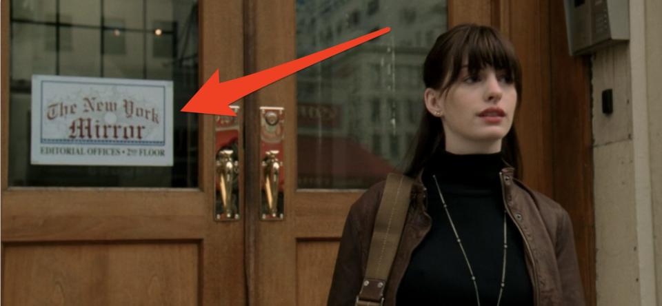 red arrow pointing to the new york mirror sign as andy walks out of the office devil wears prada