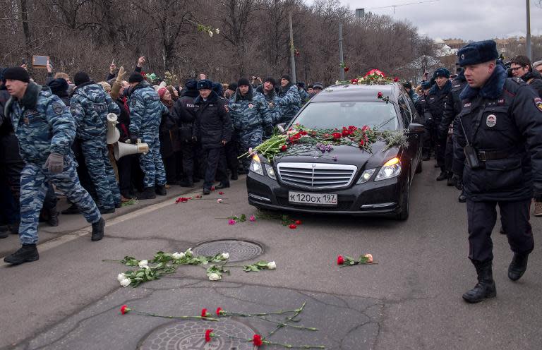 People throw flowers on a road in Moscow on March 3, 2015 as a car transports the coffin of Russian opposition leader Boris Nemtsov to the cemetery