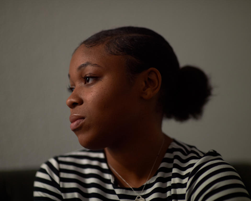 A young woman wearing a black-and-white striped shirt looks to the side.