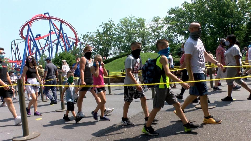 People wear masks as they arrive for Six Flags Great Adventure's opening day in Jackson Township, N.J., on July 3, 2020. The park had a delayed reopening for the summer season because of the spread of COVID-19.