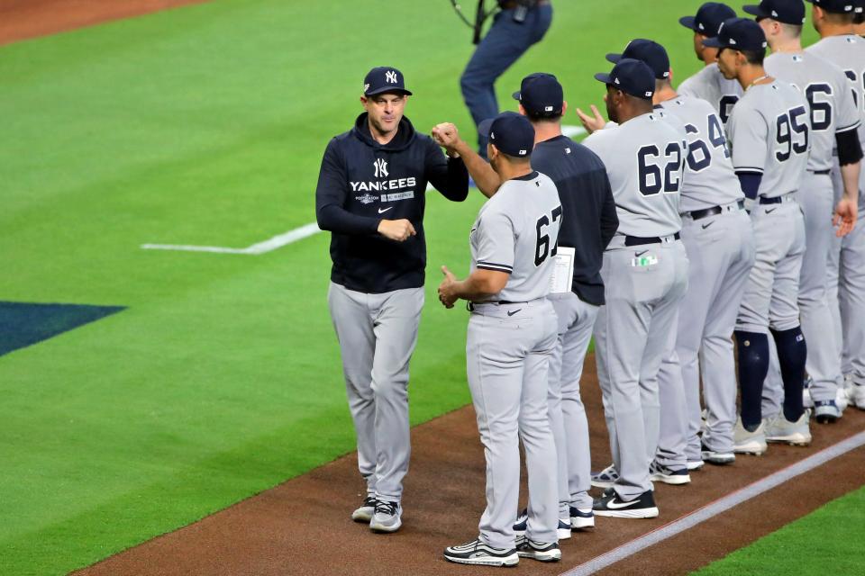 El mánager de los Yankees de Nueva York, Aaron Boone, golpea con el puño al entrenador de tercera base Luis Rojas (67) durante las presentaciones de los jugadores en la Serie de Campeonato de la Liga Americana.
