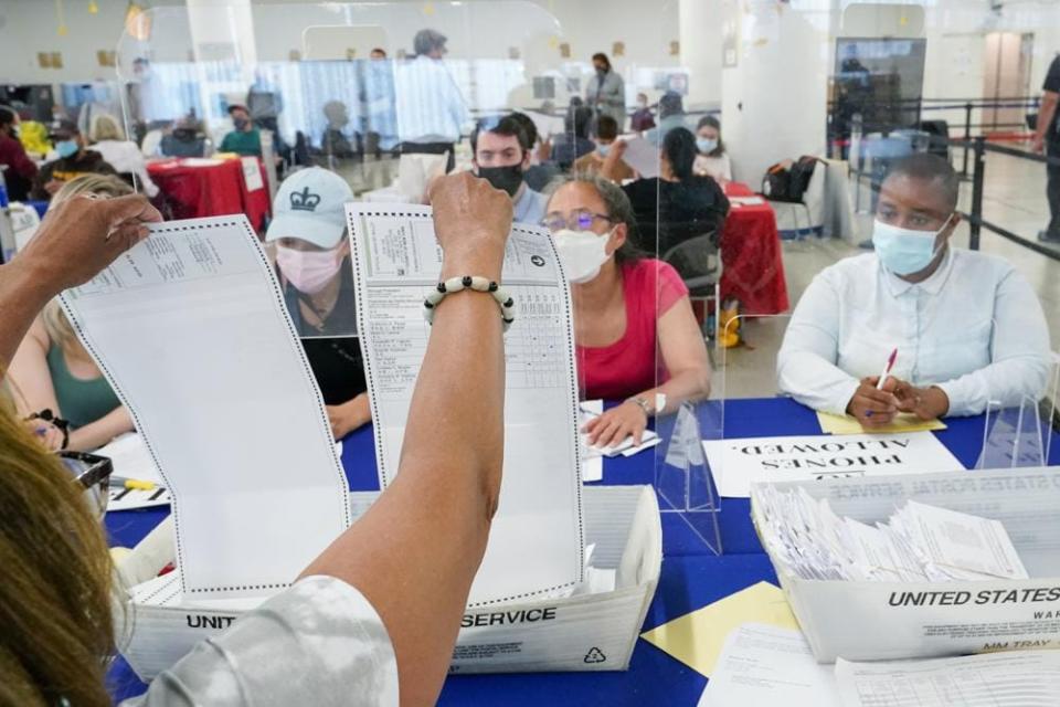 A New York City Board of Election staff member, left, shows a ballot to a campaign observers as they count absentee ballots in the primary election, Friday, July 2, 2021, in New York. (AP Photo/Mary Altaffer)