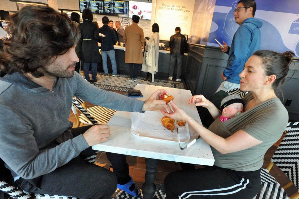 Pol Pardini, left, and Raquel Saenz and their daughter Sarai, 5 months, of Quincy, share pastries at the new Paris Baguette on Hancock Street in North Quincy, Sunday, Dec. 10, 2023.