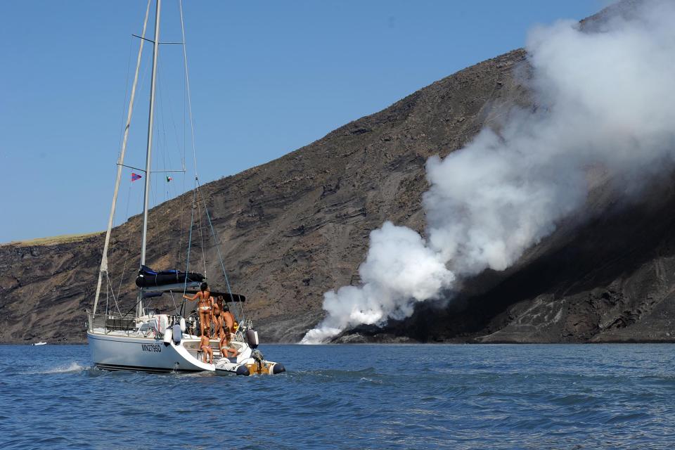 A boat sails as lava from the Stromboli volcano flows into the sea, on Aug. 9, 2014.