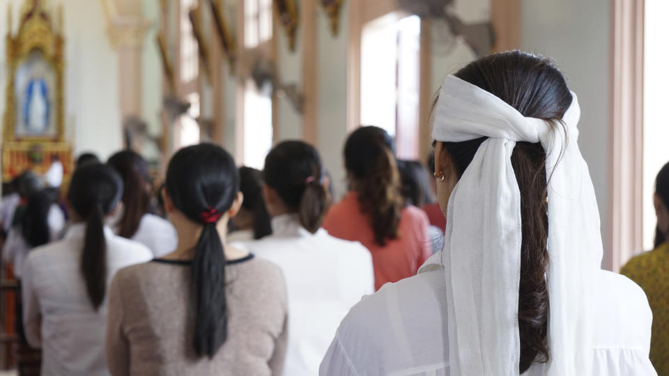 A woman wearing a white head band, traditionally worn by relatives of a deceased person during the funeral in Vietnam to show sign of mourning, attends a Sunday Mass at Phu Tang church in Yen Thanh district, Nghe An province, Vietnam Sunday, Oct. 27, 2019. The attendees pray for the victims of the U.K truck deaths in which local villagers are feared to be among the ill-fated migrants. (AP Photo/Linh Do)