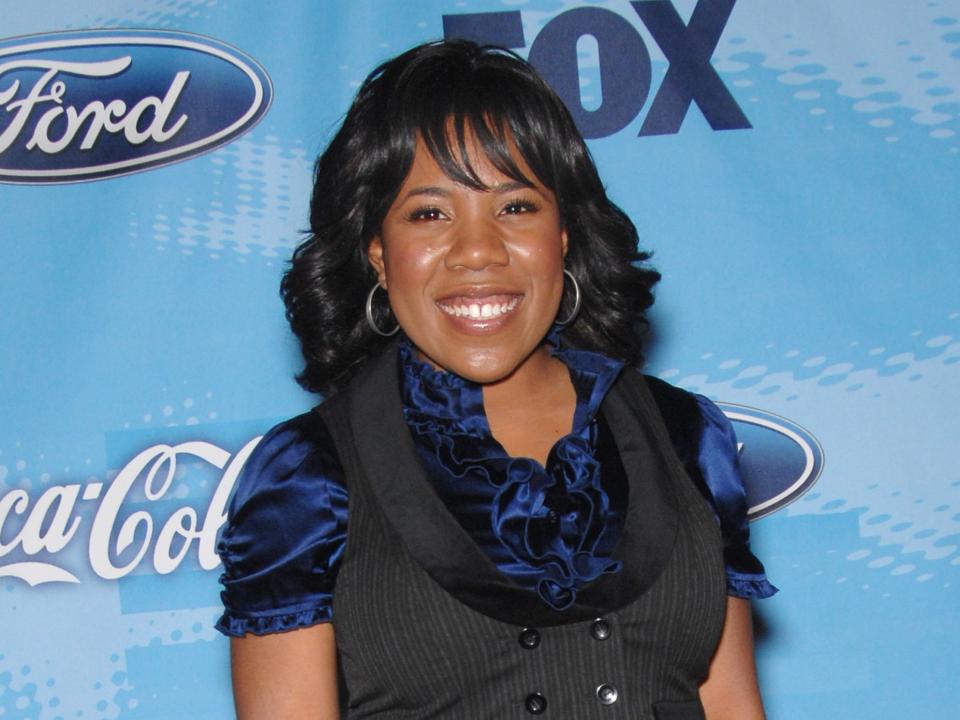 Melinda Doolittle wears a black vest and dark-blue silk shirt in front of "American Idol" background on red carpet