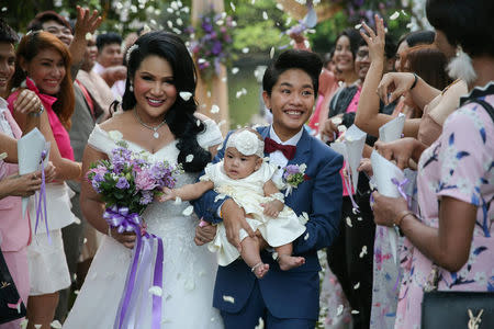 Bride Amornrat Ruamsin (L), 27, who is a transgender, holds up her five-month-old daughter with her groom Pitchaya Kachainrum (R), 16, during their wedding ceremony organised by a local TV show, in Bangkok, Thailand, February 9, 2018. The ceremony is not legally-binding as Pitchaya in under 17, the legal age for marriage in Thailand. The couple plan to officially wed after her birthday. "I've had relationships with men before, but it was not that good and I was heartbroken many times. I met Pitchaya on Facebook and I first sent her a message to introduce myself. We fell in love with each other. After living together for more then a year, we agreed to have a baby. So now we have five-month-old daughter and today we got married as our parents wanted. This is the happiest day of my life," Amornrat said. REUTERS/Athit Perawongmetha