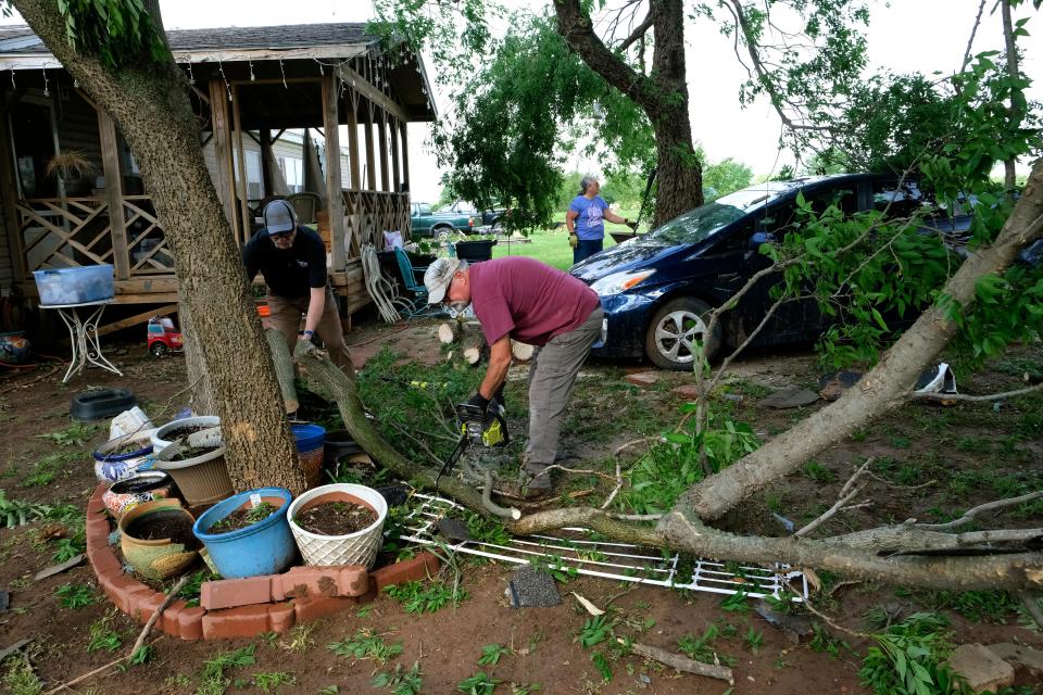 People help homeowner David Knight clean up debris Friday from a Thursday tornado in Cole.