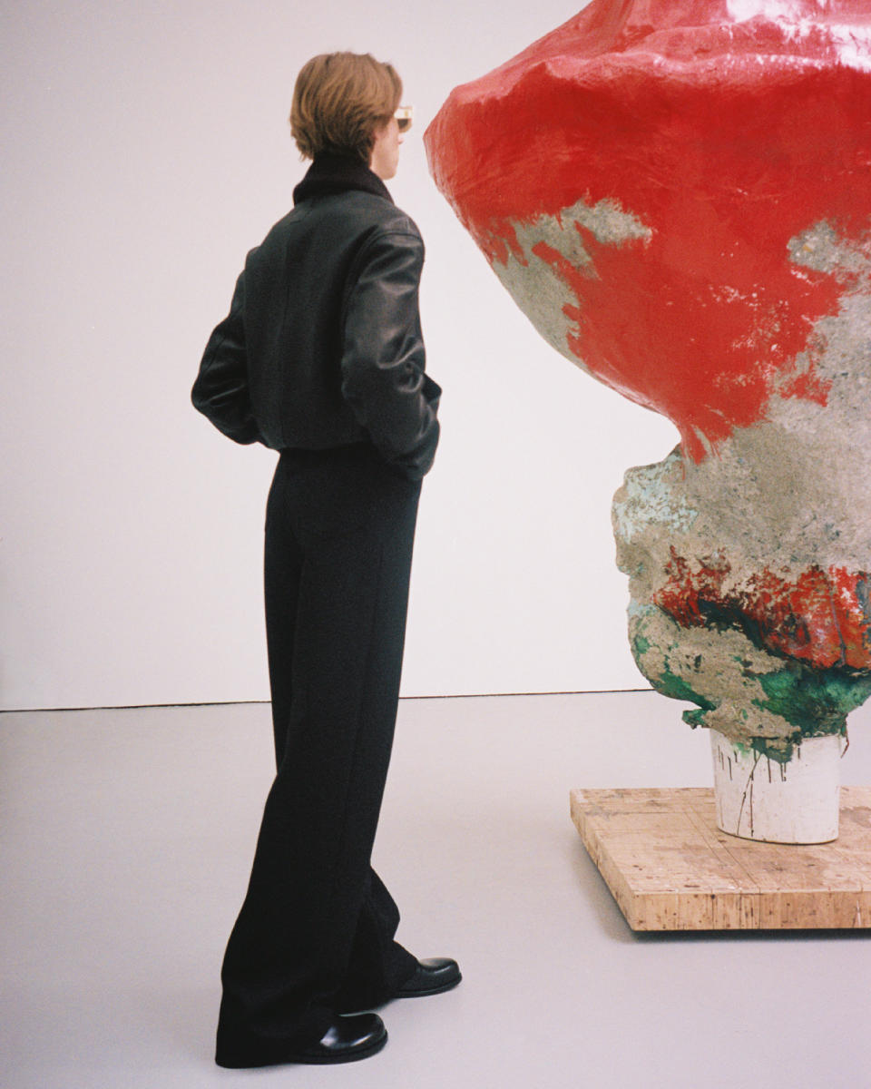 A model wearing Loewe’s spring 2024 collection while inspecting a Franz West artwork.