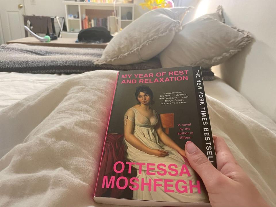 Emma Ginsberg holding a book while laying in bed