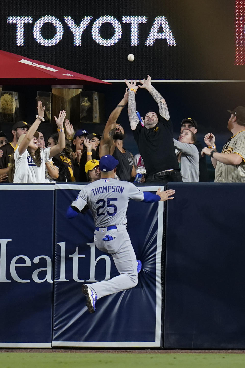 Los Angeles Dodgers left fielder Trayce Thompson (25) can't reach a home run hit by San Diego Padres' Manny Machado during the sixth inning of a baseball game Saturday, Sept. 10, 2022, in San Diego. (AP Photo/Gregory Bull)