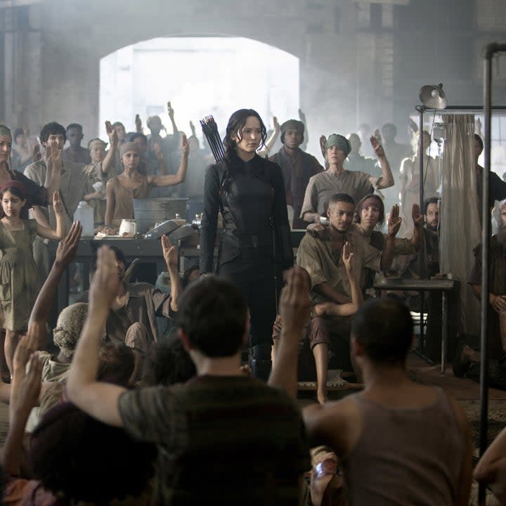 katniss in a room full of people raising their hands